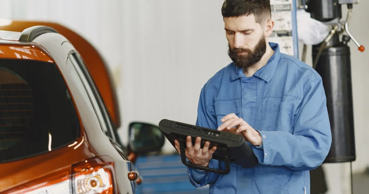 Mechaniker nutzt digitales Diagnosegerät in der KFZ-Werkstatt